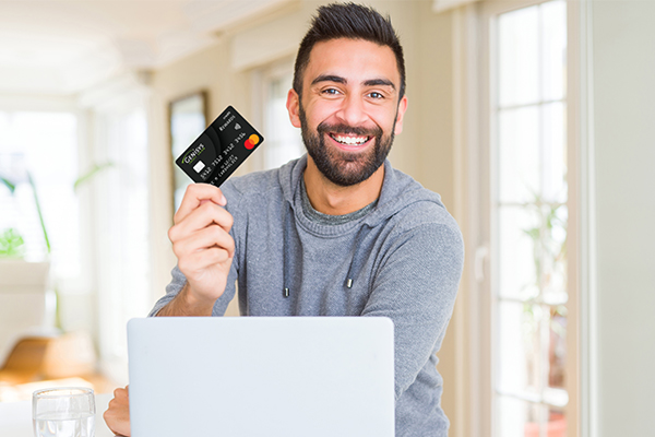 Man smiling with credit card in hand